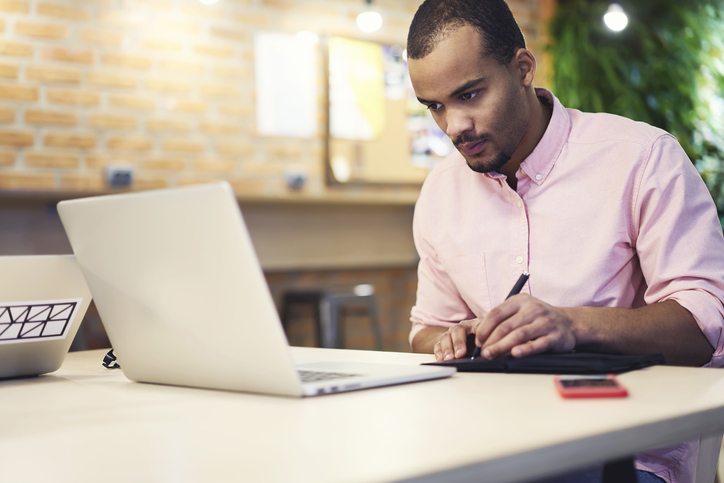 a man sits at a desk using a laptop to learn GIS software